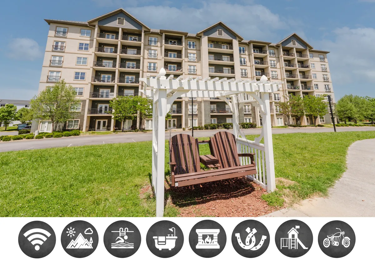 The image shows the exterior of a welcoming condo building set amidst lush greenery, with a cozy swing bench on a manicured lawn under tall trees. The peaceful atmosphere suggests relaxation opportunities in the natural surroundings, ideal for enjoying sunrise coffee or sunset views.