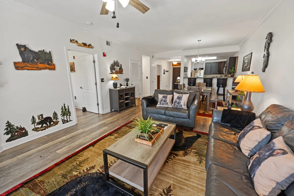 A living room with a leather sofa, coffee table, decorative wall art, and a cozy floor rug creates a welcoming atmosphere. This flexible space provides additional sleeping arrangements with its sofa sleeper and offers a comfortable spot for relaxation or socializing.