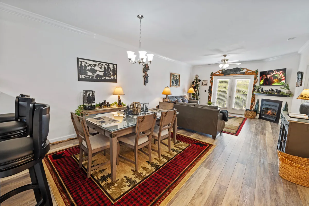 A spacious open-plan area combining a dining table set for six, a plush sofa, and a glowing fireplace. Artworks on the walls and warm lighting enhance the sense of comfort and sociability, with the living and dining spaces seamlessly connected.