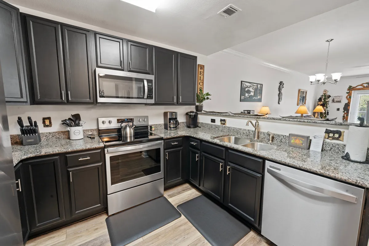A modern kitchen with granite countertops, stainless steel appliances, dark cabinetry, and an open layout ideal for cooking, entertaining, or sharing family meals together.