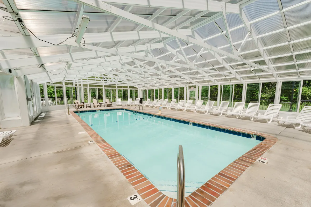 A spacious indoor swimming pool filled with natural light from large windows, surrounded by lounge chairs for relaxation. The atmosphere is calm and rejuvenating, perfect for unwinding after a day of adventure.